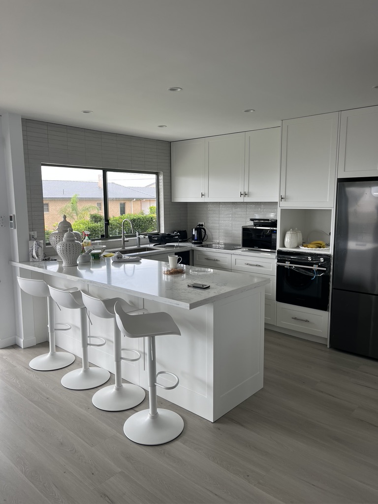 White kitchen with island seating at Halo Building Projects' Copacabana home renovation