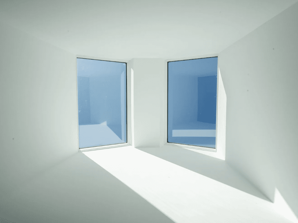 Two large windows bringing natural light into a white room