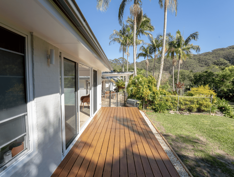 Outdoor timber deck beside a home with palm trees