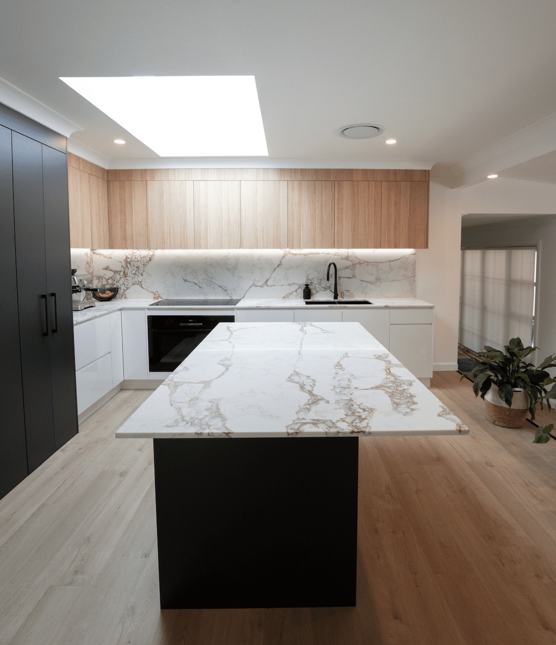 Modern kitchen with marble-look island, timber cabinetry and skylight